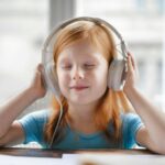 girl listening to music through headphones with her eyes closed and smiling