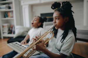girl playing trumpet accompanied by a girl playing the keyboard